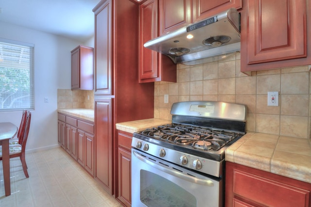 2062 Dunbar Way, Dinuba, CA 93618 - kitchen featuring stainless steel range with gas cooktop, under cabinet range hood, tile countertops, and dark brown cabinets