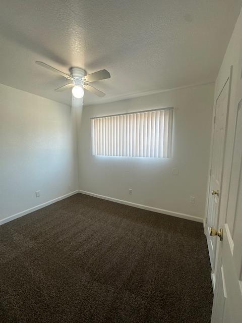 2967 E Iowa Ave, Fresno, CA 93701 - empty room with a ceiling fan, dark carpet, and a textured ceiling