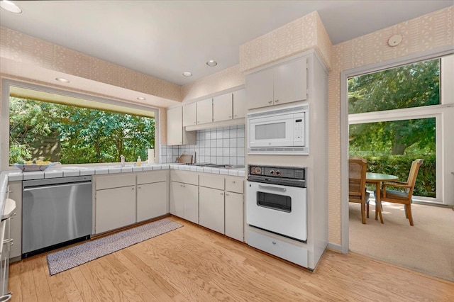 5532 N El Adobe Dr, Fresno, CA 93711 - kitchen with white appliances, tasteful backsplash, white cabinets, light wood-type flooring, and tile countertops