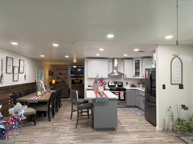 605 E Davis Dr, Dinuba, CA 93618 - kitchen with stainless steel gas range oven, wall chimney exhaust hood, freestanding refrigerator, light countertops, and gray cabinets