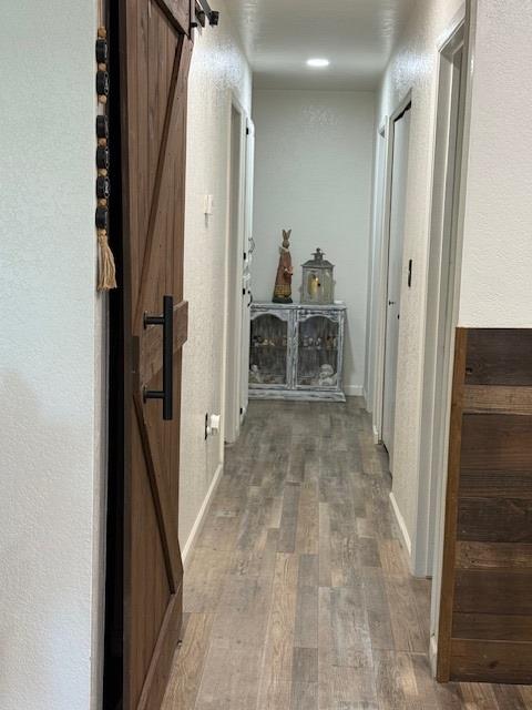 605 E Davis Dr, Dinuba, CA 93618 - hall featuring a barn door, wood finished floors, and a textured wall