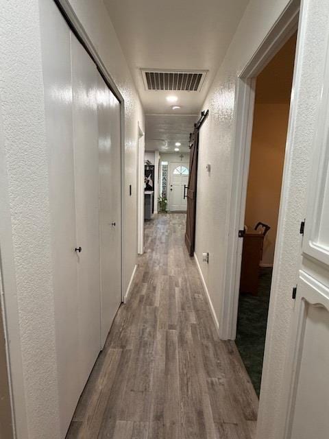 605 E Davis Dr, Dinuba, CA 93618 - hallway with wood finished floors, a barn door, and a textured wall
