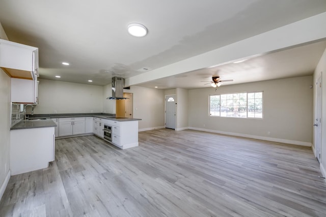 17189 Iona Ave, Lemoore, CA 93245 - kitchen featuring wall chimney range hood, dark countertops, open floor plan, oven, and a peninsula