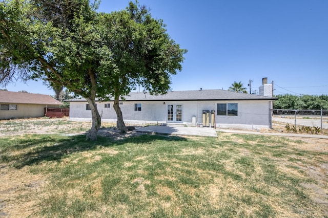 17189 Iona Ave, Lemoore, CA 93245 - back of property with french doors, a patio area, a chimney, and stucco siding