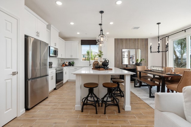 1473 Bloom Ln, Clovis, CA 93619 - kitchen with stainless steel appliances, recessed lighting, a chandelier, a breakfast bar area, and white cabinets