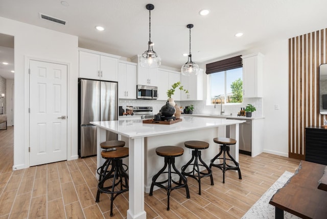 1473 Bloom Ln, Clovis, CA 93619 - kitchen with stainless steel appliances, light wood-type flooring, backsplash, a kitchen bar, and recessed lighting