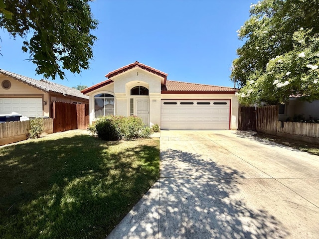 4688 W Weldon Ave, Fresno, CA 93722 - mediterranean / spanish-style house featuring a tile roof, stucco siding, an attached garage, and driveway