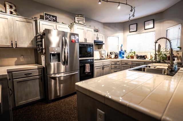 10080 N Dearing Ave, Fresno, CA 93730 - kitchen with black appliances, tile counters, decorative backsplash, under cabinet range hood, and a peninsula