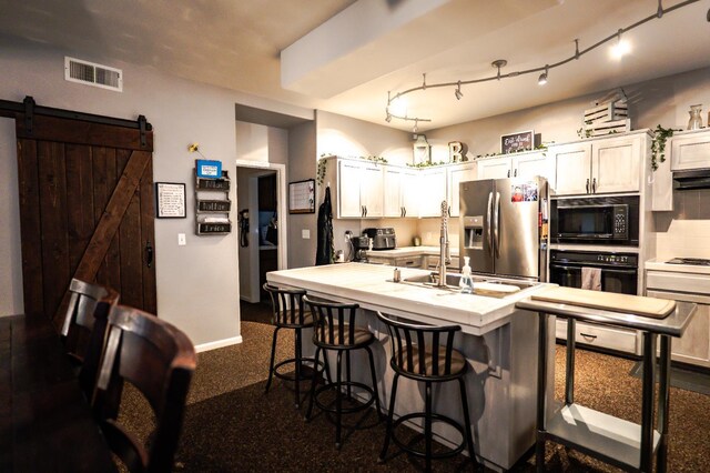 10080 N Dearing Ave, Fresno, CA 93730 - kitchen with black appliances, a barn door, a kitchen breakfast bar, white cabinetry, and tasteful backsplash