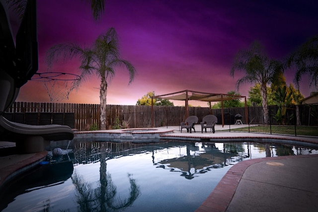 10080 N Dearing Ave, Fresno, CA 93730 - pool at dusk featuring a fenced backyard, an in-ground hot tub, a water slide, and a patio