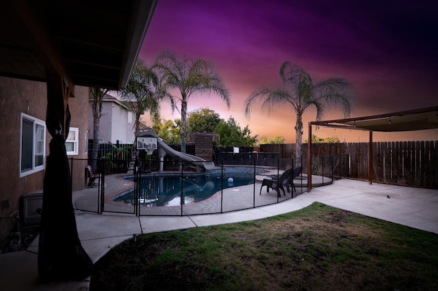 10080 N Dearing Ave, Fresno, CA 93730 - pool at dusk with a water slide, a fenced backyard, and a patio area