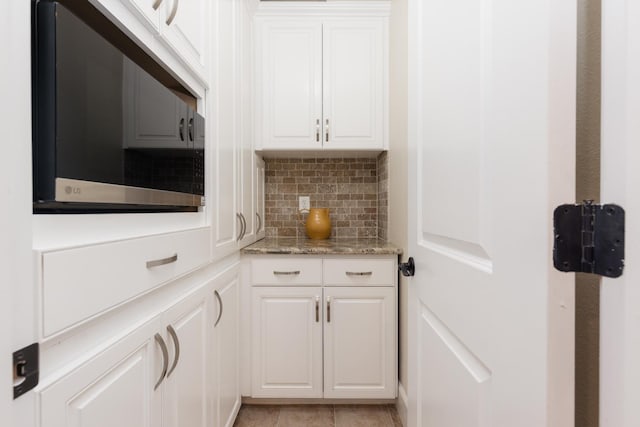 1199 E Cole Ave, Fresno, CA 93720 - kitchen featuring stainless steel microwave, backsplash, white cabinetry, and light stone counters