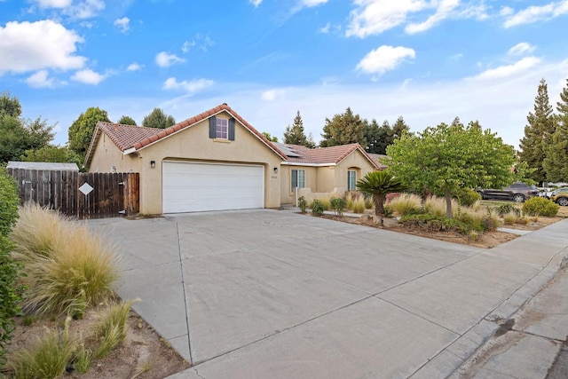2540 E Seeger Ave, Visalia, CA 93292 - view of front of house with stucco siding, solar panels, driveway, a garage, and a tiled roof