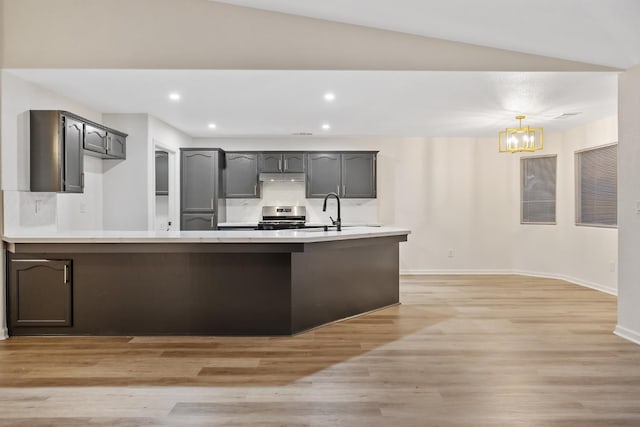 2540 E Seeger Ave, Visalia, CA 93292 - kitchen featuring stainless steel range oven, under cabinet range hood, a chandelier, light countertops, and light wood finished floors