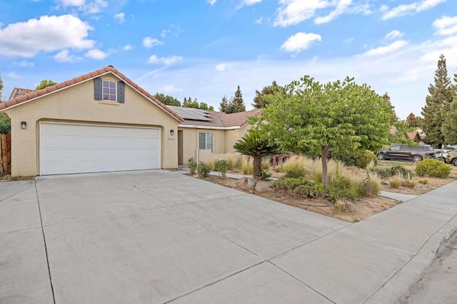 2540 E Seeger Ave, Visalia, CA 93292 - view of front facade with concrete driveway, roof mounted solar panels, a garage, stucco siding, and a tiled roof