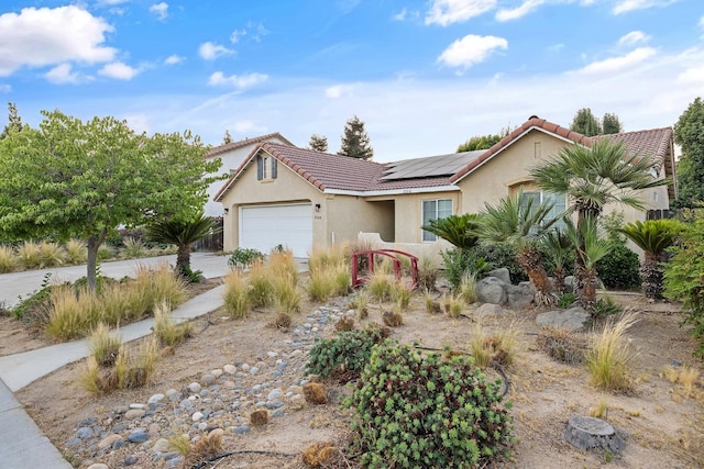 2540 E Seeger Ave, Visalia, CA 93292 - view of front of home featuring roof mounted solar panels, stucco siding, a garage, driveway, and a tile roof