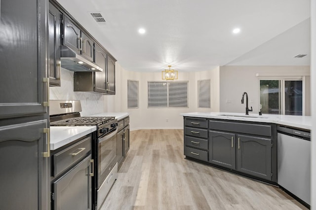 2540 E Seeger Ave, Visalia, CA 93292 - kitchen featuring appliances with stainless steel finishes, under cabinet range hood, light wood-type flooring, light countertops, and backsplash