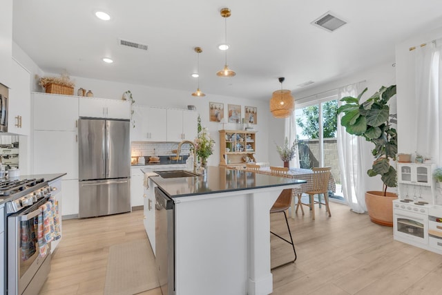 1961 Oak Ln, Clovis, CA 93611 - kitchen with appliances with stainless steel finishes, backsplash, light wood-type flooring, dark countertops, and recessed lighting