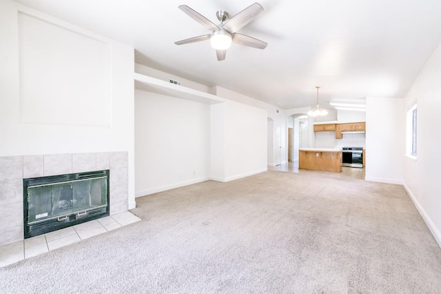 5537 W Oswego Ave, Fresno, CA 93722 - unfurnished living room featuring light colored carpet, a fireplace, ceiling fan, arched walkways, and a chandelier