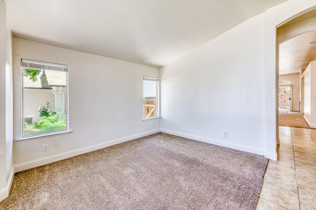 5537 W Oswego Ave, Fresno, CA 93722 - spare room with arched walkways, healthy amount of natural light, light tile patterned floors, and light colored carpet