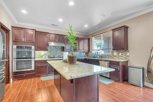 3017 W Oleander Ave, Fresno, CA 93706 - kitchen with appliances with stainless steel finishes, light wood-style flooring, under cabinet range hood, a center island, and backsplash