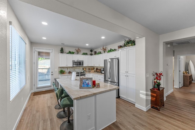 7387 E Robinson Ave, Fresno, CA 93737 - kitchen featuring appliances with stainless steel finishes, light wood-style floors, white cabinets, a breakfast bar, and recessed lighting