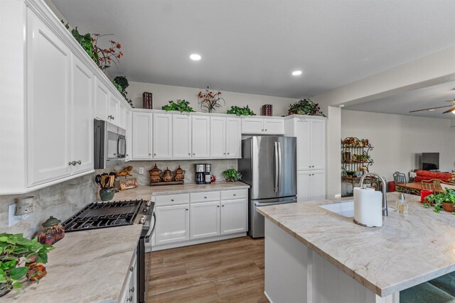 7387 E Robinson Ave, Fresno, CA 93737 - kitchen with appliances with stainless steel finishes, white cabinets, recessed lighting, tasteful backsplash, and light wood-type flooring