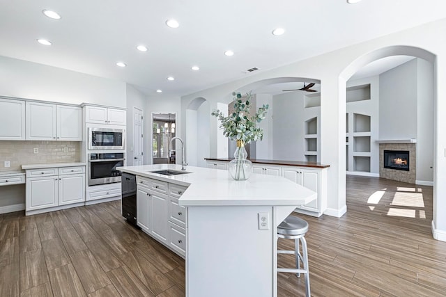 1552 N Gateway Ave, Clovis, CA 93619 - kitchen with stainless steel appliances, wood finished floors, recessed lighting, a center island with sink, and a glass covered fireplace