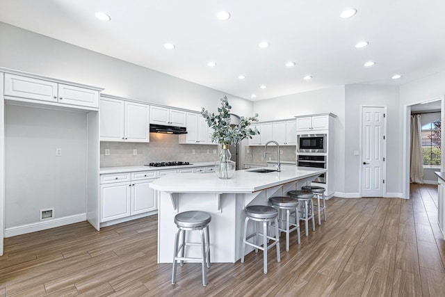 1552 N Gateway Ave, Clovis, CA 93619 - kitchen featuring appliances with stainless steel finishes, under cabinet range hood, white cabinetry, light wood-style flooring, and recessed lighting