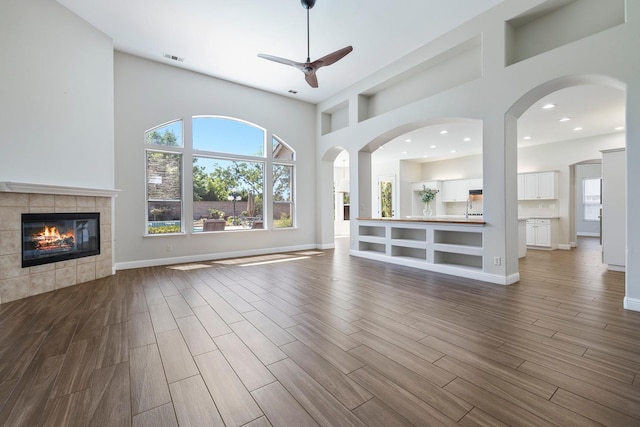 1552 N Gateway Ave, Clovis, CA 93619 - unfurnished living room with a ceiling fan, a fireplace, dark wood-style flooring, a towering ceiling, and recessed lighting
