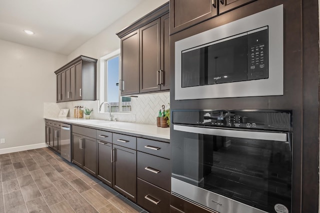 974 Talus Way S, Madera, CA 93636 - kitchen with appliances with stainless steel finishes, backsplash, light countertops, dark brown cabinetry, and wood finished floors