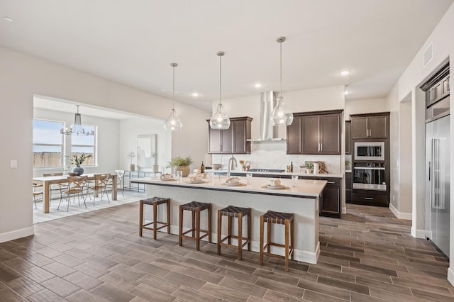 974 Talus Way S, Madera, CA 93636 - kitchen with wall chimney range hood, built in appliances, dark brown cabinets, decorative backsplash, and wood tiled floors