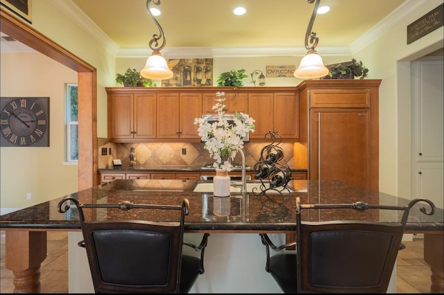1682 N Dutch Ave, Clovis, CA 93619 - kitchen featuring brown cabinetry, an island with sink, tasteful backsplash, a breakfast bar, and pendant lighting