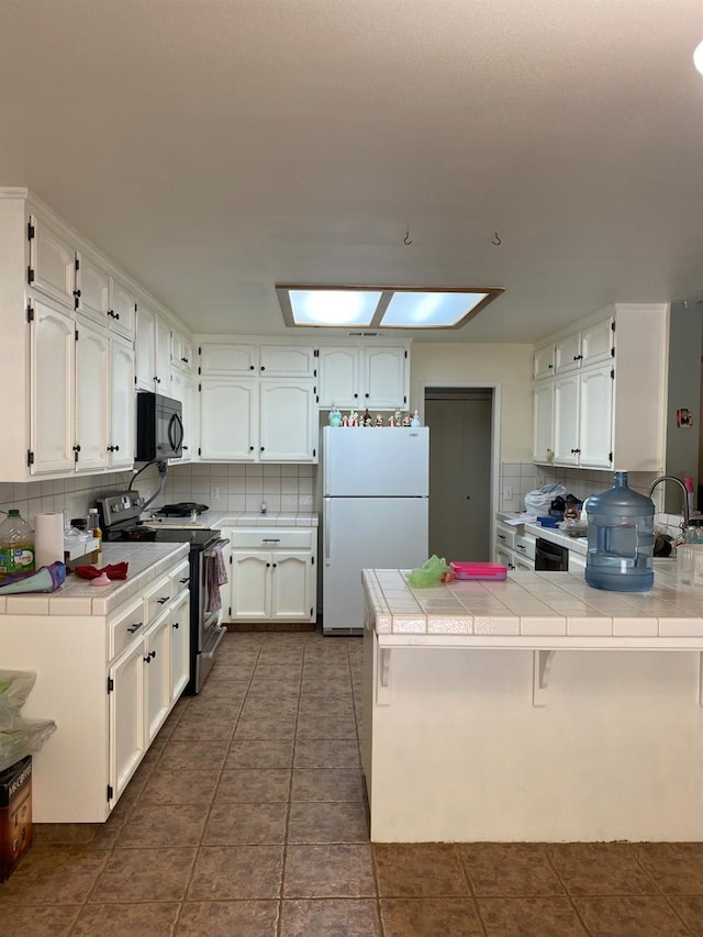 5288 N Piedra Rd N, Sanger, CA 93657 - kitchen featuring freestanding refrigerator, black microwave, stainless steel range, a peninsula, and tile countertops