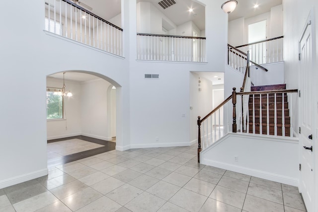 1090 Clara Ave, Fowler, CA 93625 - foyer with arched walkways, tile patterned floors, stairs, a high ceiling, and a chandelier