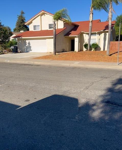 6324 N Brix, Fresno, CA 93722 - view of front of home with stucco siding, an attached garage, a tiled roof, and concrete driveway