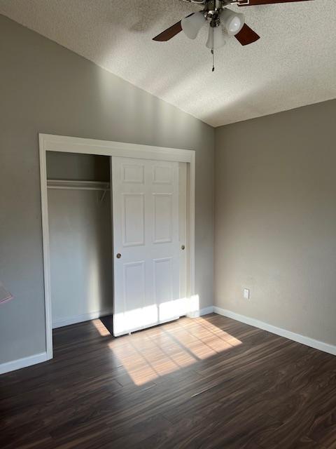 6324 N Brix, Fresno, CA 93722 - unfurnished bedroom featuring a textured ceiling, dark wood-style flooring, lofted ceiling, a closet, and ceiling fan