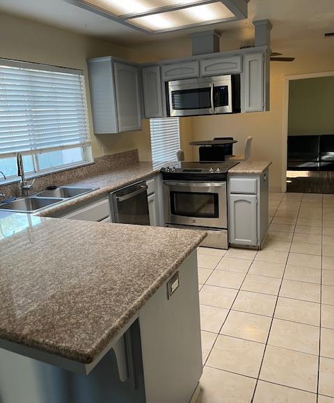 6324 N Brix, Fresno, CA 93722 - kitchen with stainless steel appliances, light tile patterned flooring, a peninsula, and gray cabinetry