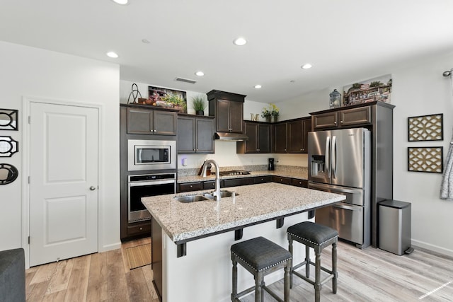 4146 Dennis Ave, Clovis, CA 93619 - kitchen with stainless steel appliances, a kitchen breakfast bar, dark brown cabinets, a center island with sink, and light wood-style floors