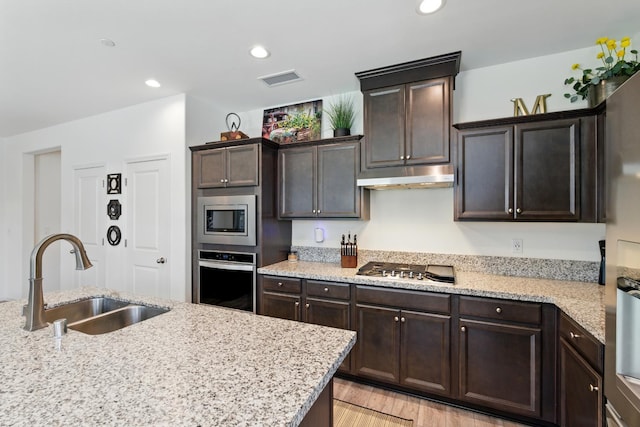 4146 Dennis Ave, Clovis, CA 93619 - kitchen with appliances with stainless steel finishes, under cabinet range hood, dark brown cabinets, light stone counters, and recessed lighting