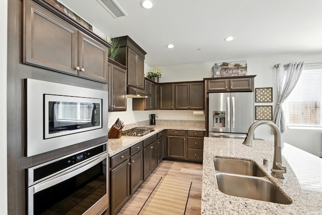4146 Dennis Ave, Clovis, CA 93619 - kitchen with stainless steel appliances, dark brown cabinets, light wood-style floors, light stone counters, and recessed lighting