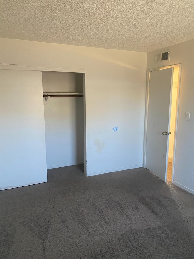 2673 N Marty Ave, Fresno, CA 93722 - unfurnished bedroom featuring a textured ceiling, dark colored carpet, and a closet