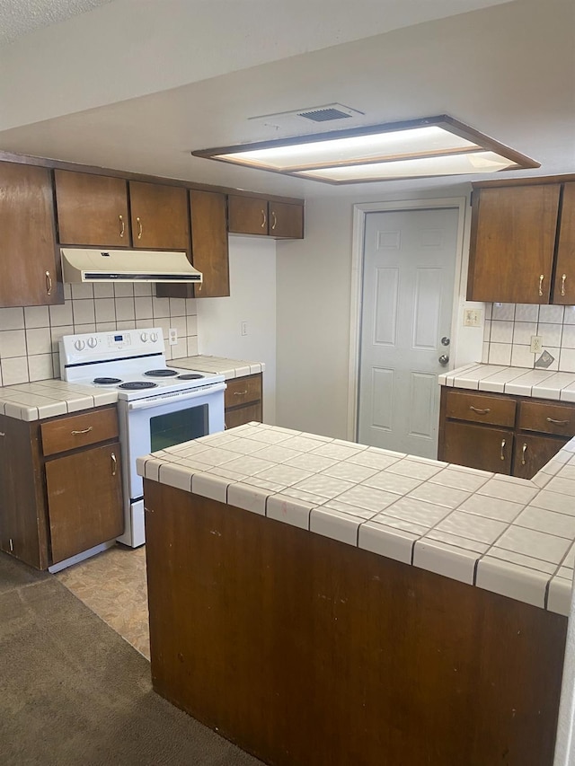 2673 N Marty Ave, Fresno, CA 93722 - kitchen featuring under cabinet range hood, white range with electric cooktop, tasteful backsplash, and tile countertops