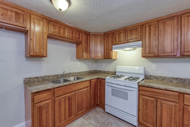 1437 N San Pablo Ave, Fresno, CA 93728 - kitchen featuring gas range gas stove, under cabinet range hood, brown cabinetry, light tile patterned floors, and light stone countertops