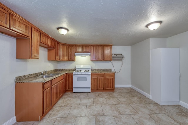 1437 N San Pablo Ave, Fresno, CA 93728 - kitchen with white gas range oven, under cabinet range hood, brown cabinets, stone counters, and a textured ceiling