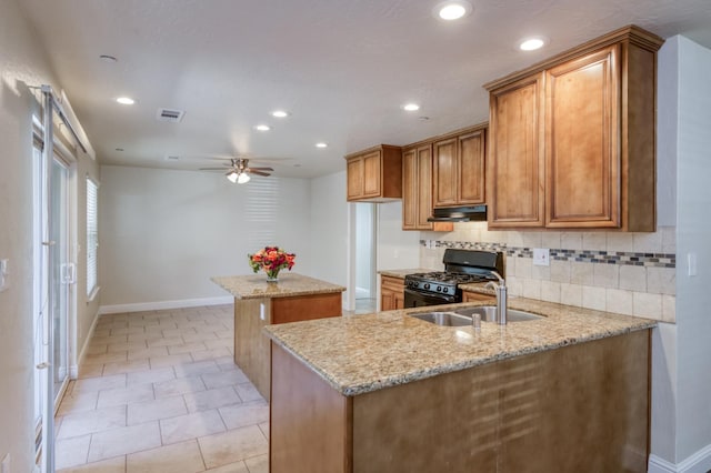 1437 N San Pablo Ave, Fresno, CA 93728 - kitchen with black gas range, a center island, brown cabinets, under cabinet range hood, and recessed lighting