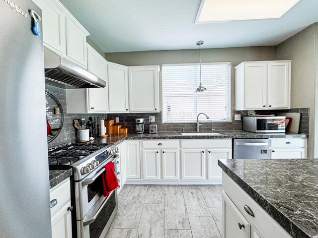 2457 Carson Ave, Clovis, CA 93611 - kitchen featuring appliances with stainless steel finishes, under cabinet range hood, white cabinetry, decorative backsplash, and pendant lighting
