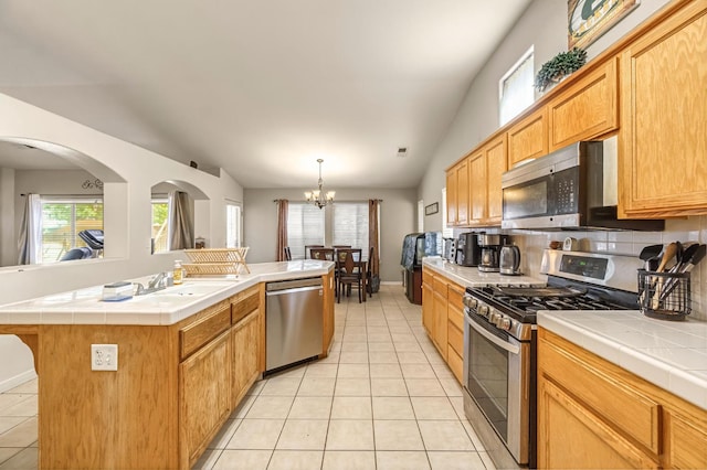3787 Via Capitola, Madera, CA 93637 - kitchen with stainless steel appliances, tile countertops, vaulted ceiling, light tile patterned floors, and decorative backsplash