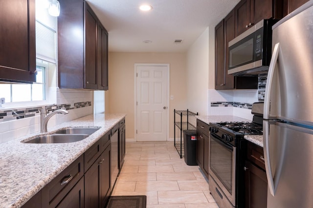 4115 E Montecito Ave, Fresno, CA 93702 - kitchen featuring appliances with stainless steel finishes, tasteful backsplash, dark brown cabinets, light stone countertops, and recessed lighting