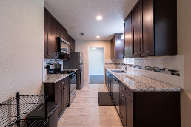 4115 E Montecito Ave, Fresno, CA 93702 - kitchen featuring stainless steel appliances, backsplash, light stone counters, dark brown cabinetry, and recessed lighting